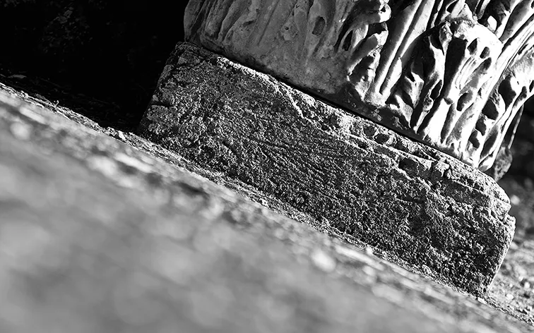 Base e dettaglio scolpito di un'antica colonna di marmo in primo piano, in bianco e nero