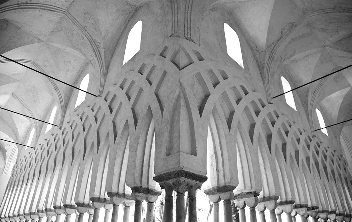 Chiostro con esili colonne e archi ogivali intrecciati, soffitto a volte con finestre, in bianco e nero