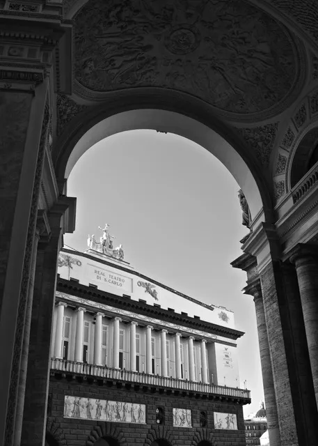 La facciata del Teatro di San Carlo inquadrata da un arco della Galleria Umberto I, con la quadriga sul coronamento, in bianco e nero