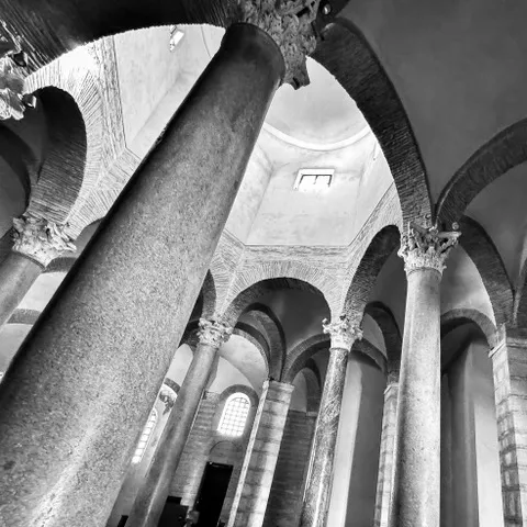 Colonne antiche con capitelli corinzi e arcate in mattoni sotto una cupola con finestre, riprese dal basso, in bianco e nero