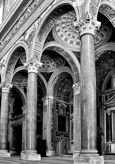 Navata di una chiesa monumentale con alte colonne di granito e arconi a cassettoni, in bianco e nero