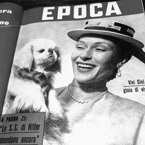 Una pagina d'epoca del settimanale Epoca con una donna sorridente in cappello e un cagnolino pechinese, in bianco e nero