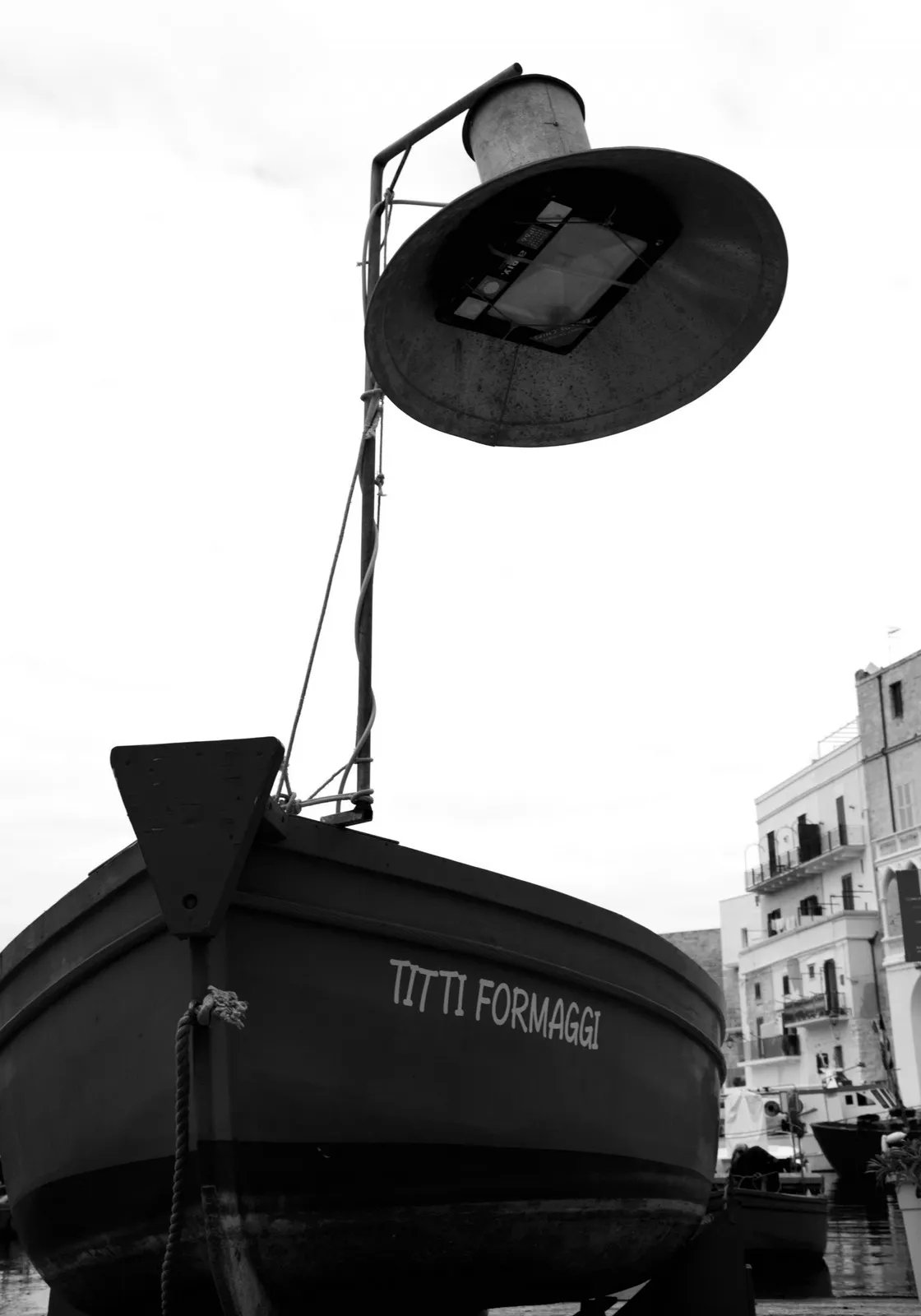 Vista dal basso della prua di una barca con una grande lampada da pesca montata sopra, in bianco e nero