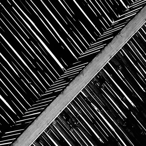 Motivo astratto di canne o listelli in diagonale, divisi da una trave che separa due orditure opposte, in bianco e nero